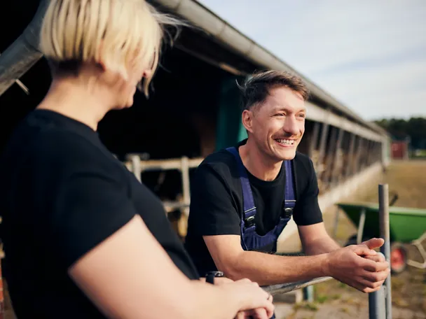 Zwei Personen unterhalten sich neben einem Kuhstall Zwei Personen unterhalten sich neben einem Kuhstall